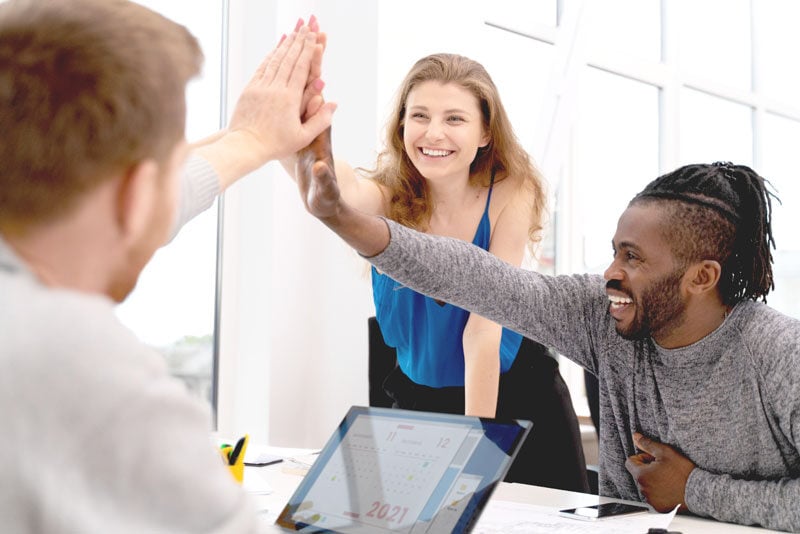 People in an office giving high fives, representing the collaborative spirit essential for small business success and strategic growth and strategic advisory, accounting precision, and tax expertise, offering a holistic solution for businesses.